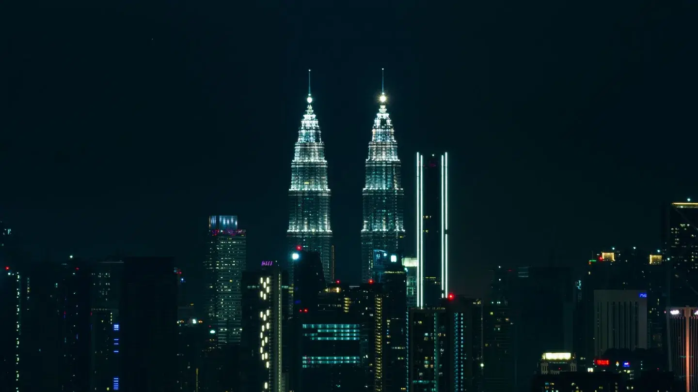 Petronas Towers illuminated above Kuala Lumpur at night